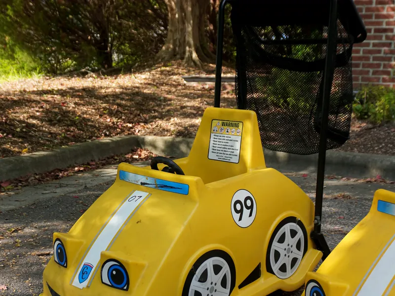 Yellow CuddleCar child cart with a steering wheel and a basket