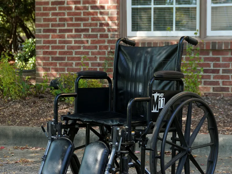 Black wheelchair with large rear wheels and swing-away leg rests